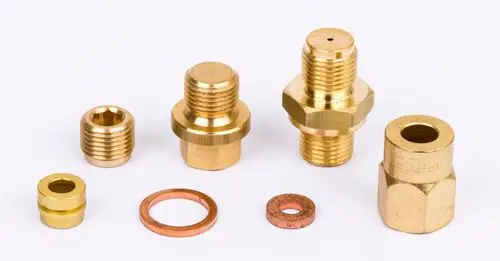 Verschiedene Messingfittings und Dichtungen auf einem weißen Hintergrund, geeignet für den Einbau in dem Danfoss Steuerungs-Set.
